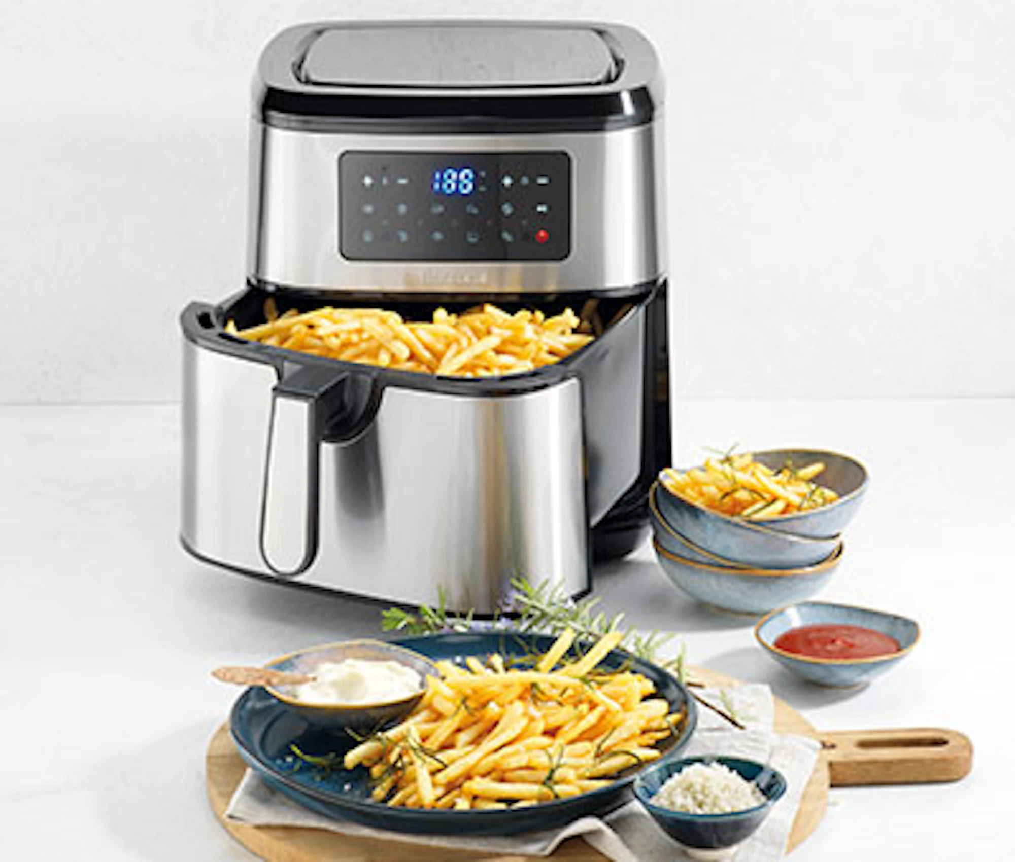 Robins Kitchen air fryer with pull-out basket filled with fries, displayed alongside plated chips and dipping sauces on a countertop