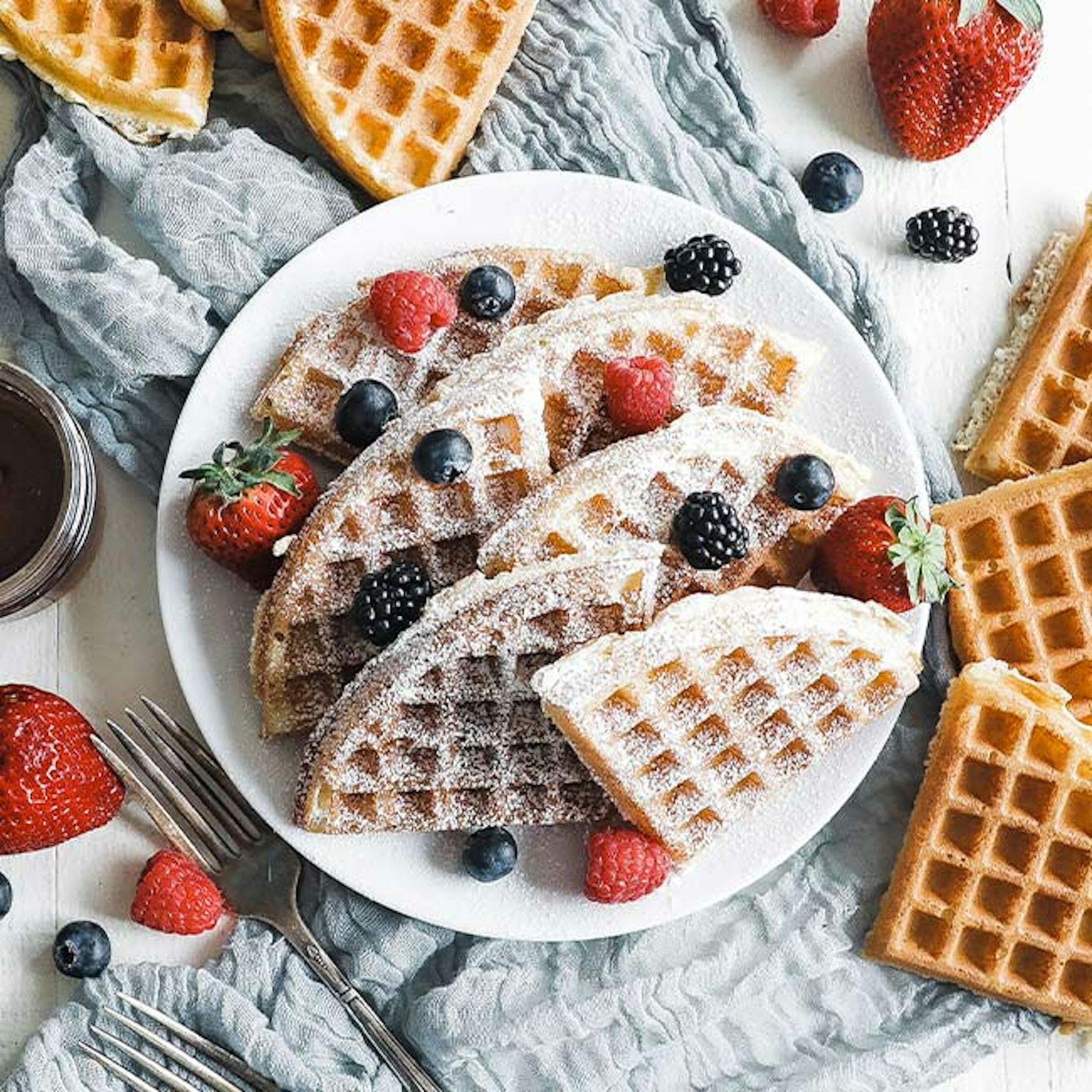 belgium waffles on plate with strawberry and blueberry toppings