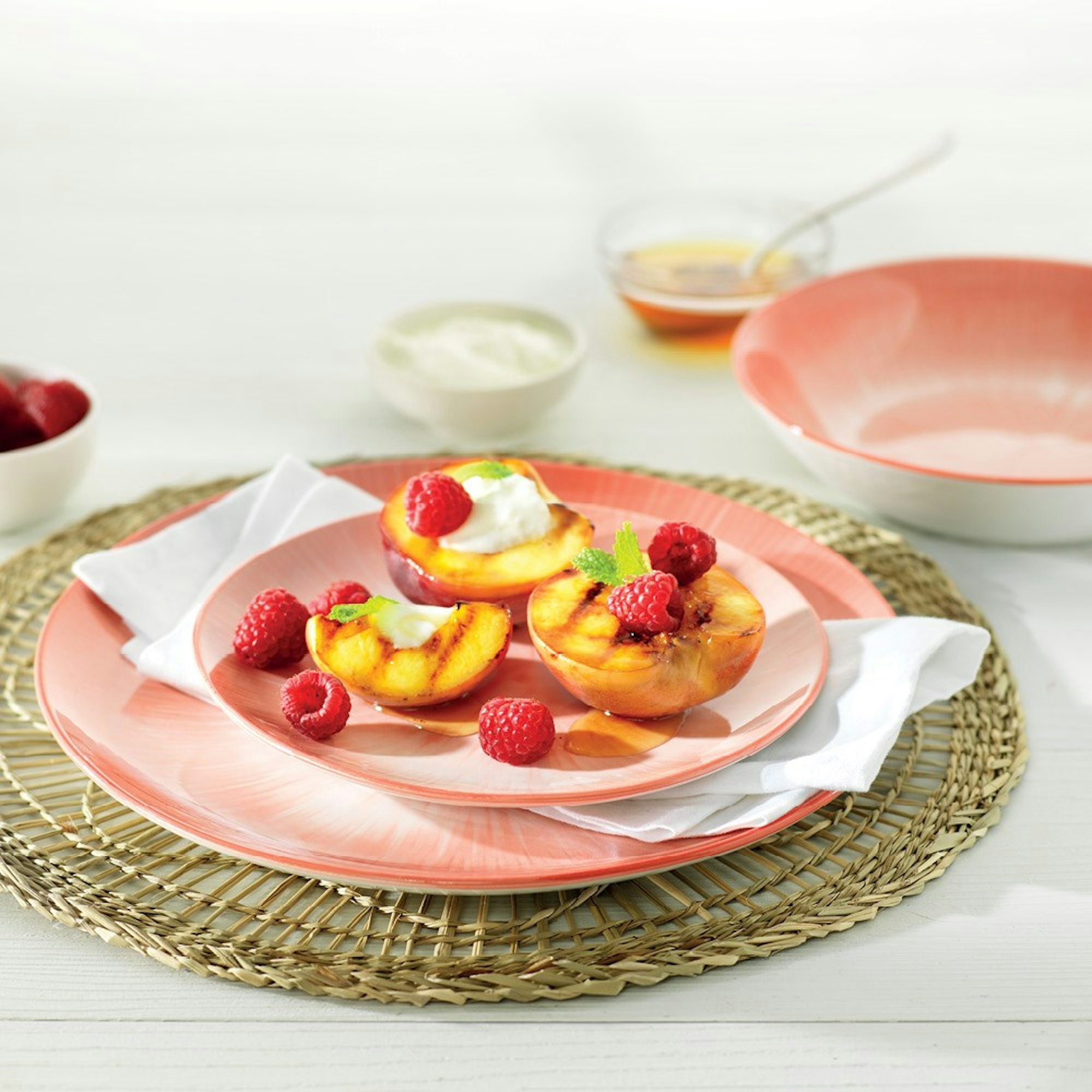 pink dinner set on rattan placemat with fruit