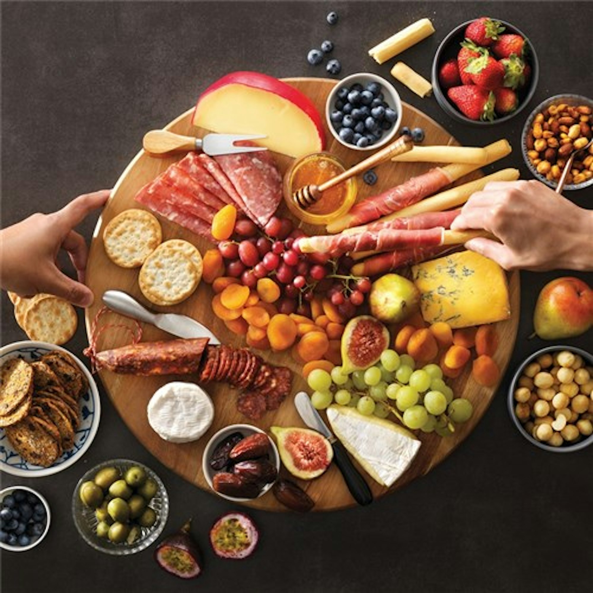 Round grazing platter board filled with charcuterrie cheese, meats and fruits