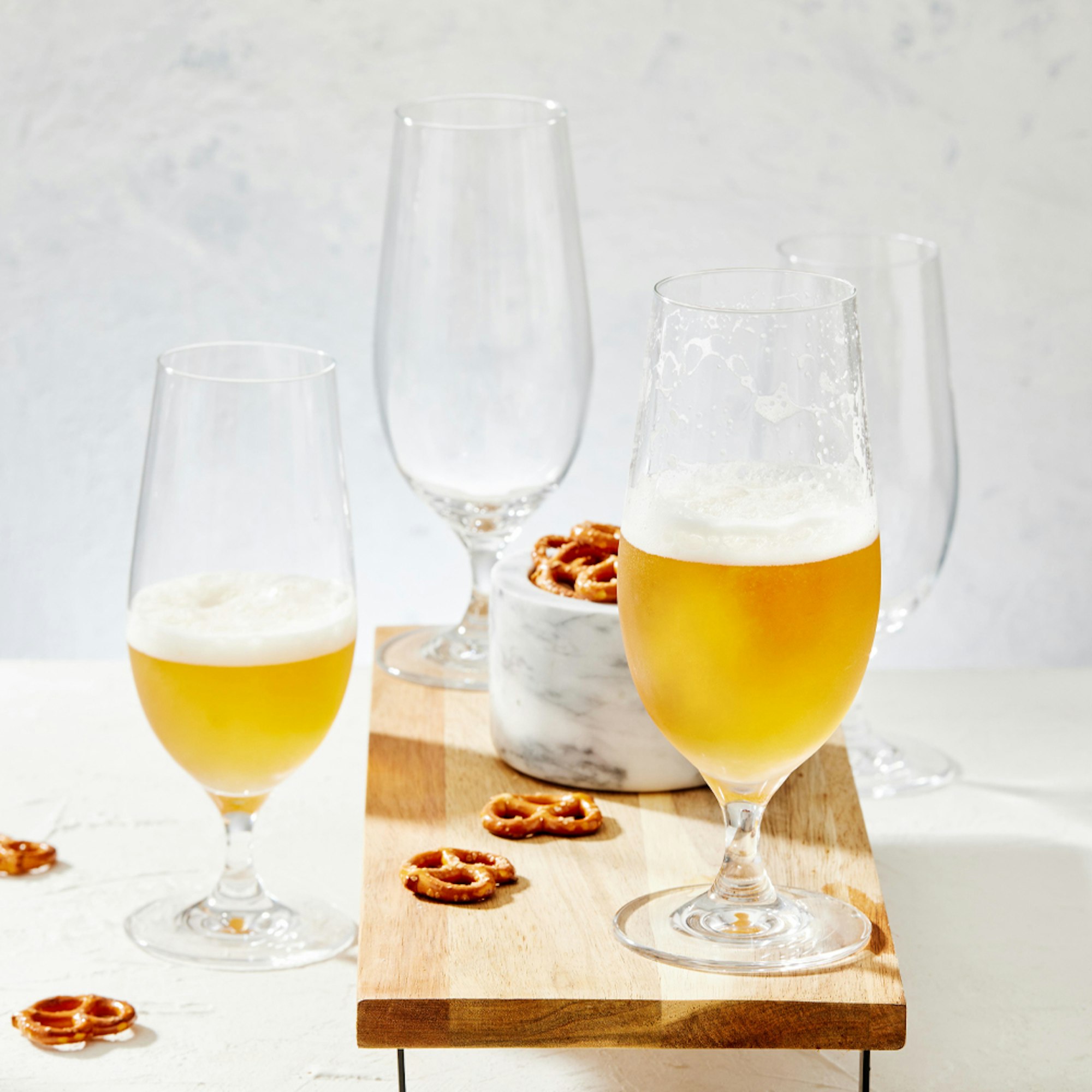 Beer glasses on wooden plank with pretzels