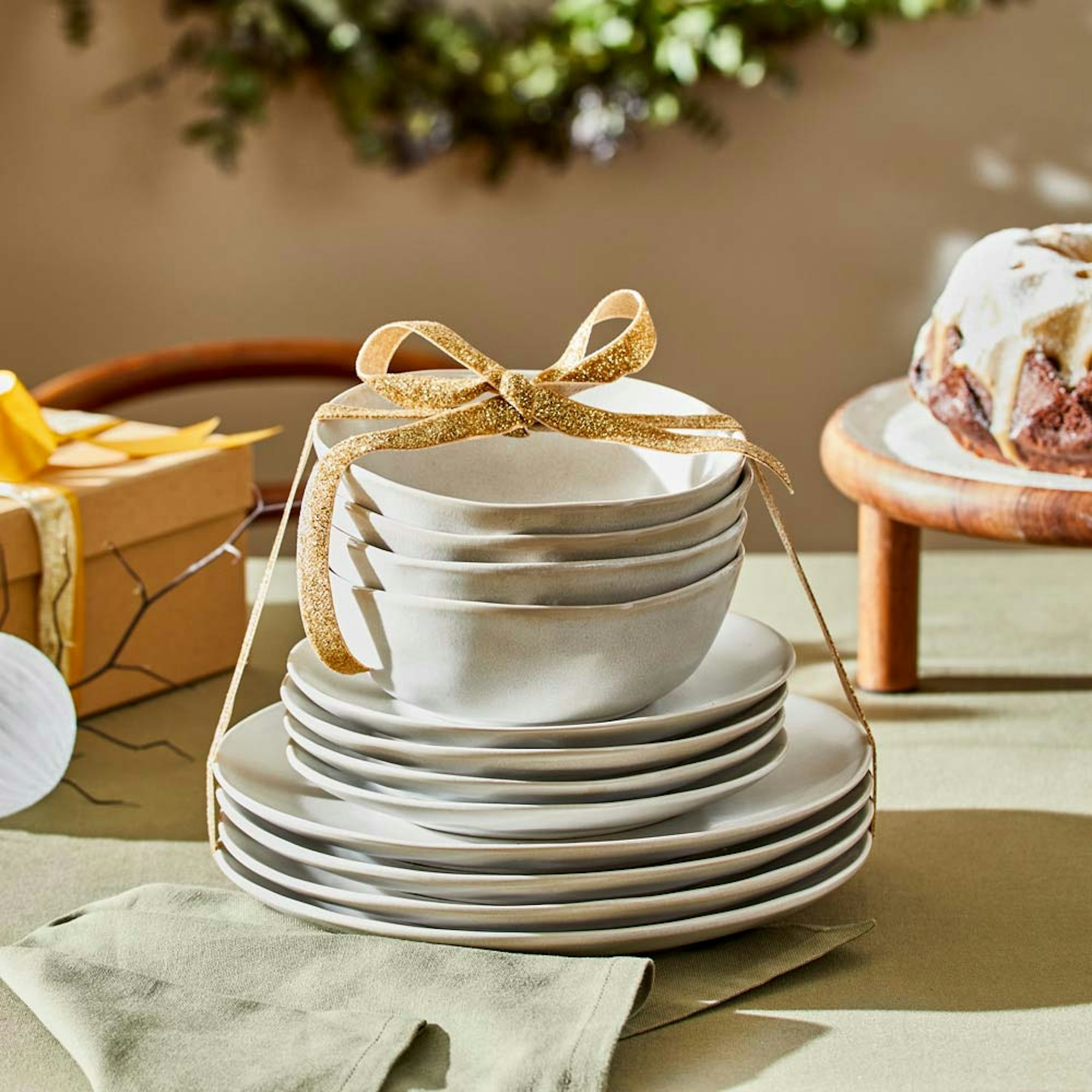 Christmas Gift Guide 2023 Robins Kitchen. Dinner set stacked wrapped with gold ribbon.