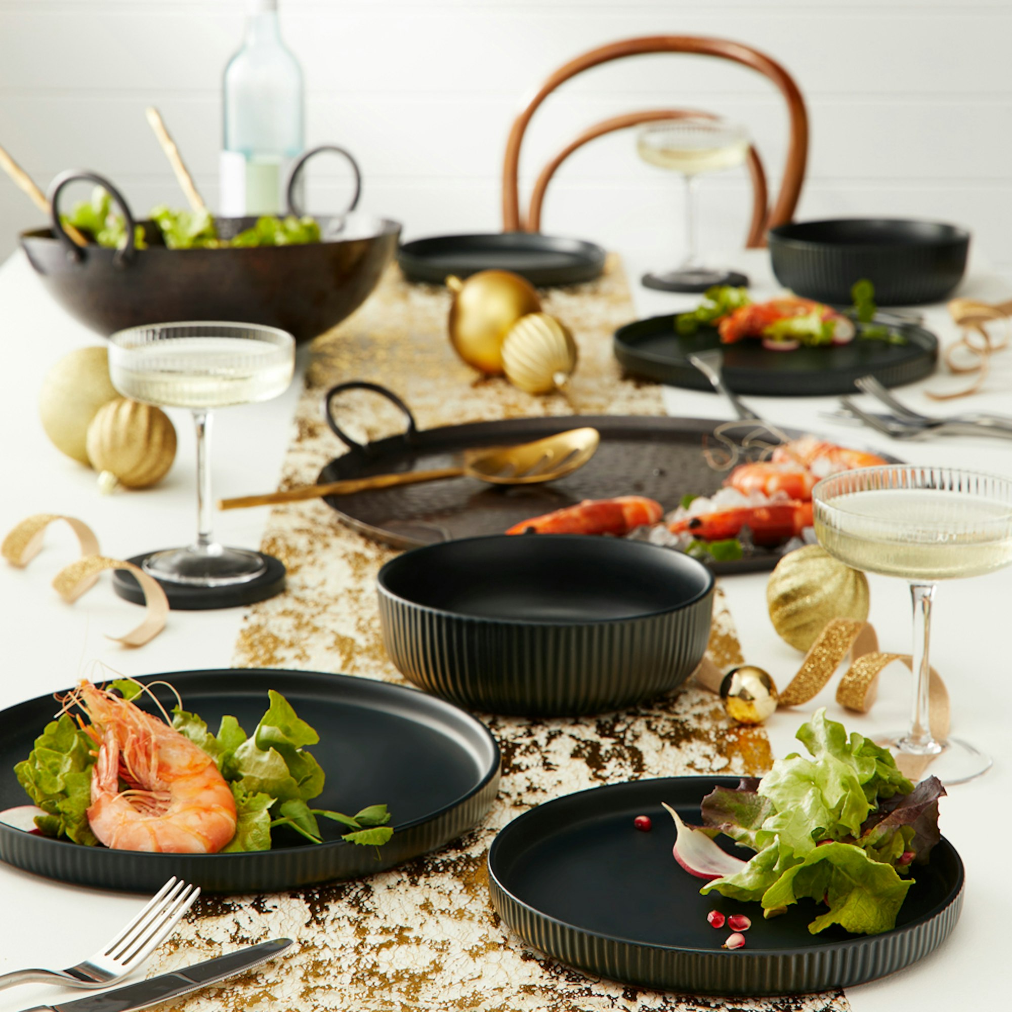 long table setting with gold table ware and black dinner set