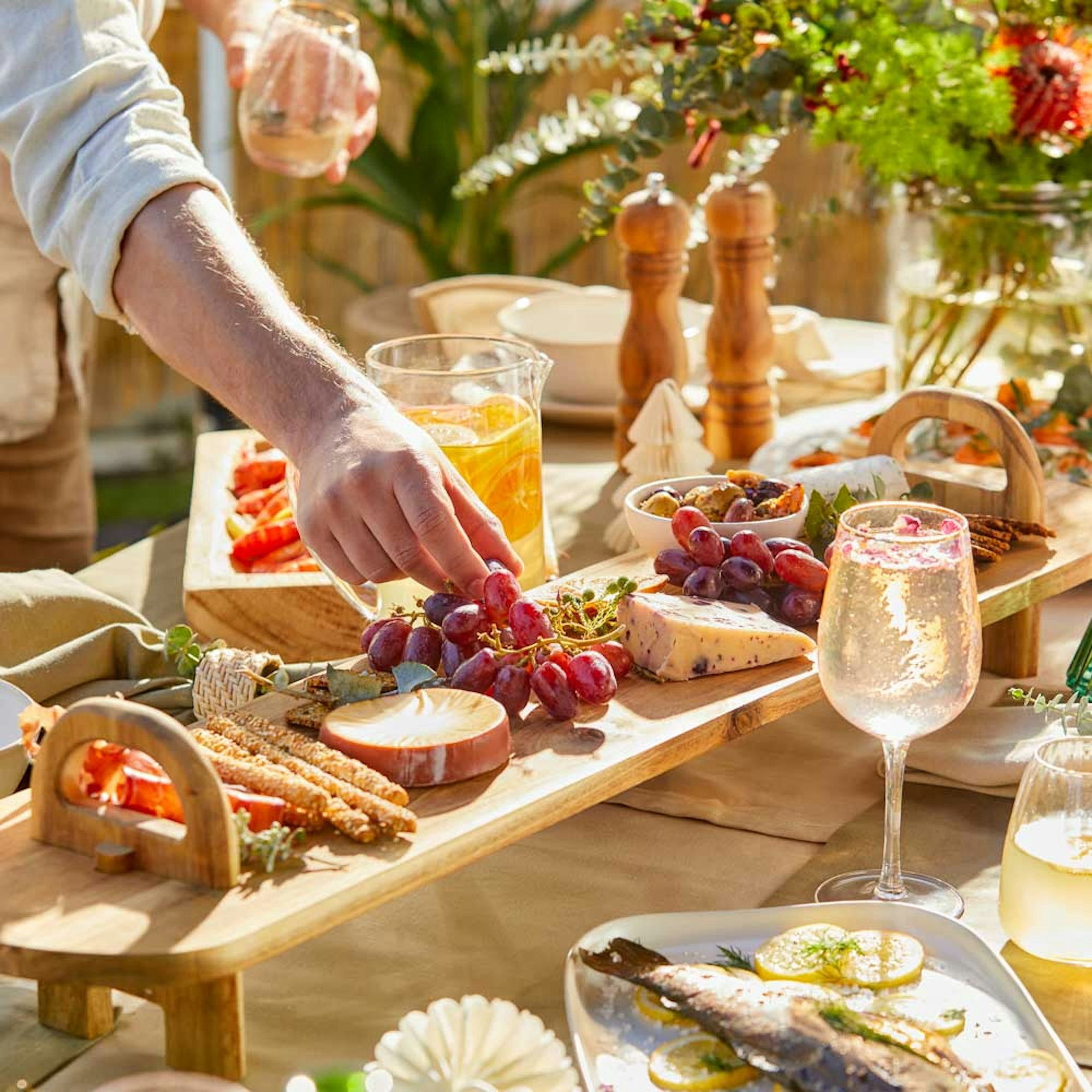 Man picking grapes from serving plank - Perfect Serving Platters for Entertaining blog