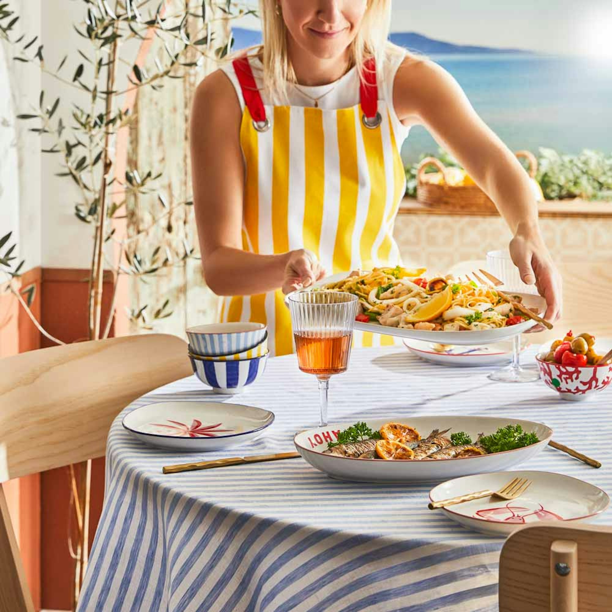 Woman serving pasta on oval platter - Perfect Serving Platters for Entertaining blog