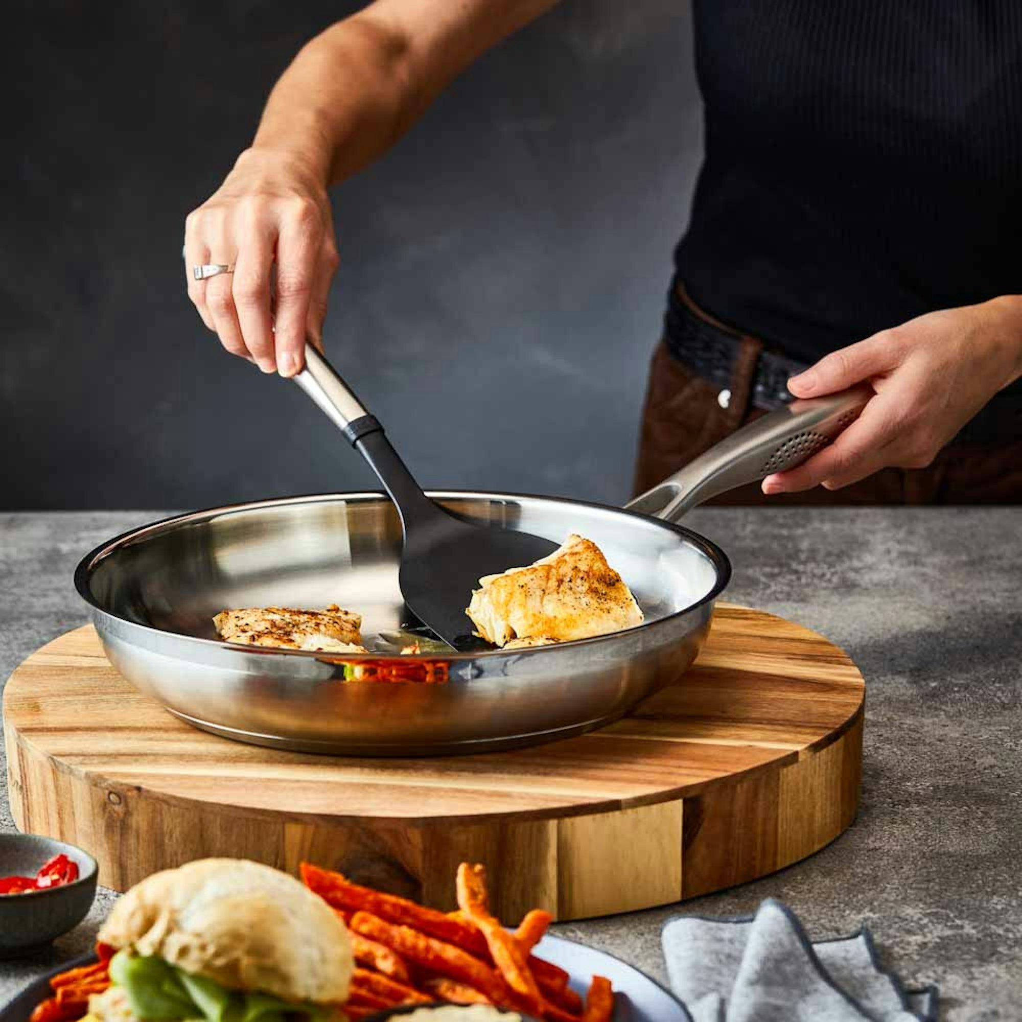 Woman cooking fish in stainless steel frypan - What Size Fry Pan Do I Need blog