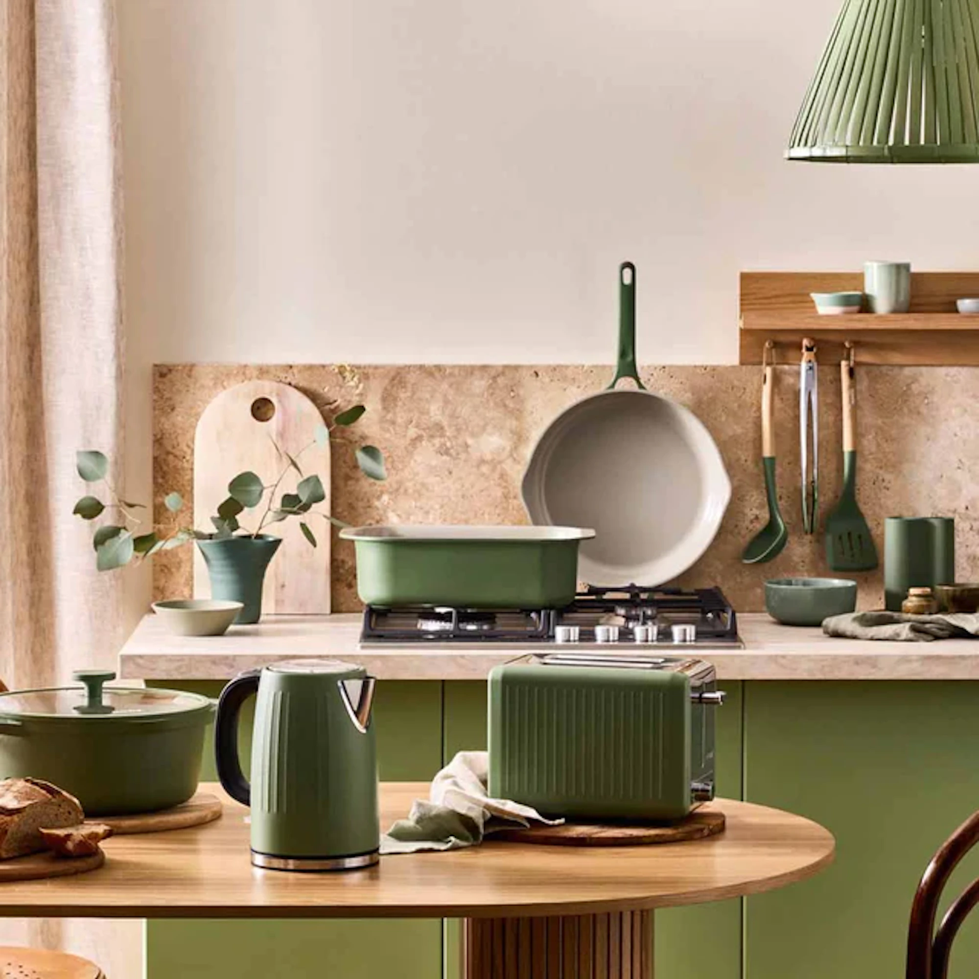 NOOK cookware set including a kettle, toaster, casserole dish and saucepan arranged in a modern kitchen with matching green cabinetry and utensils