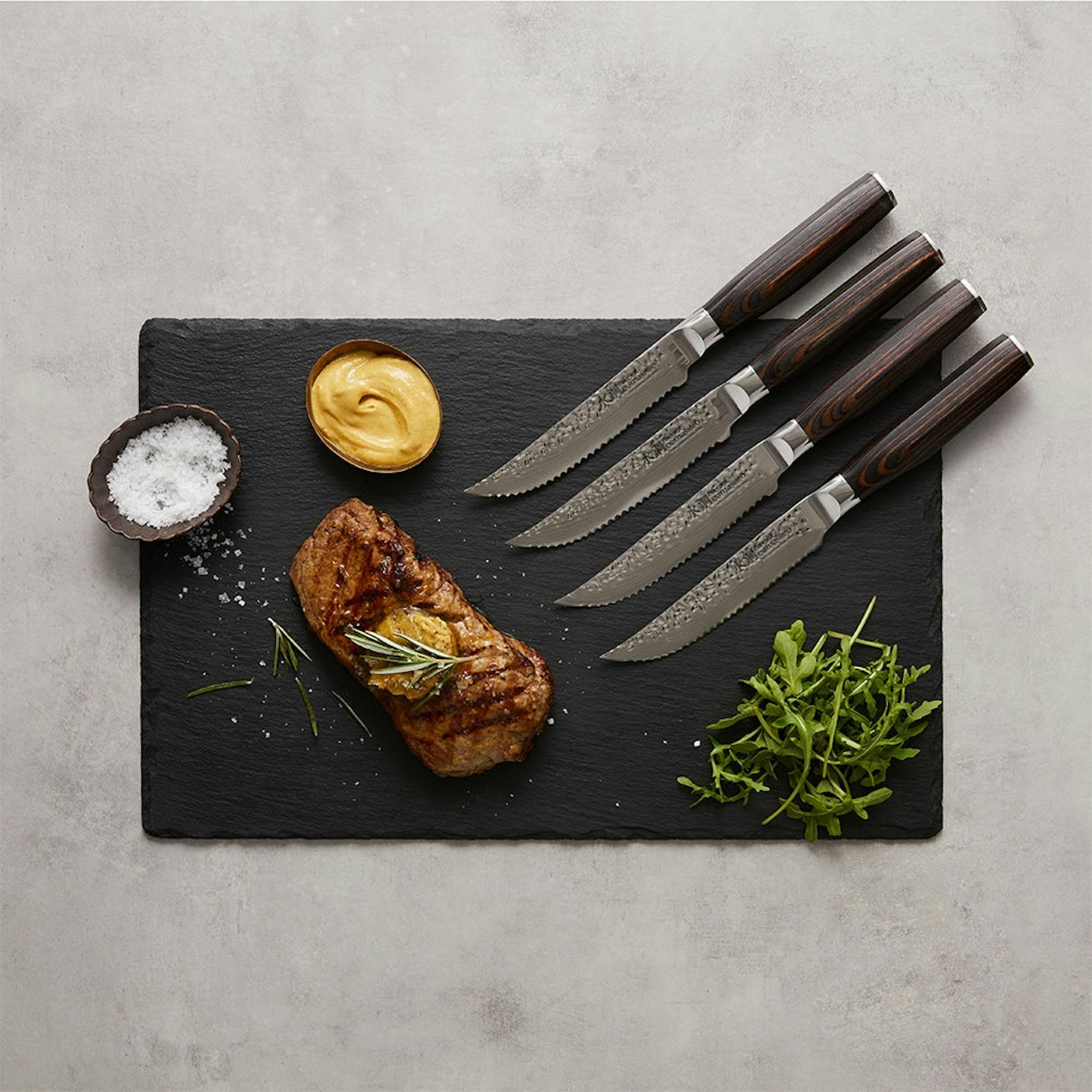 Grill reverse seared steak on black board with steak knives