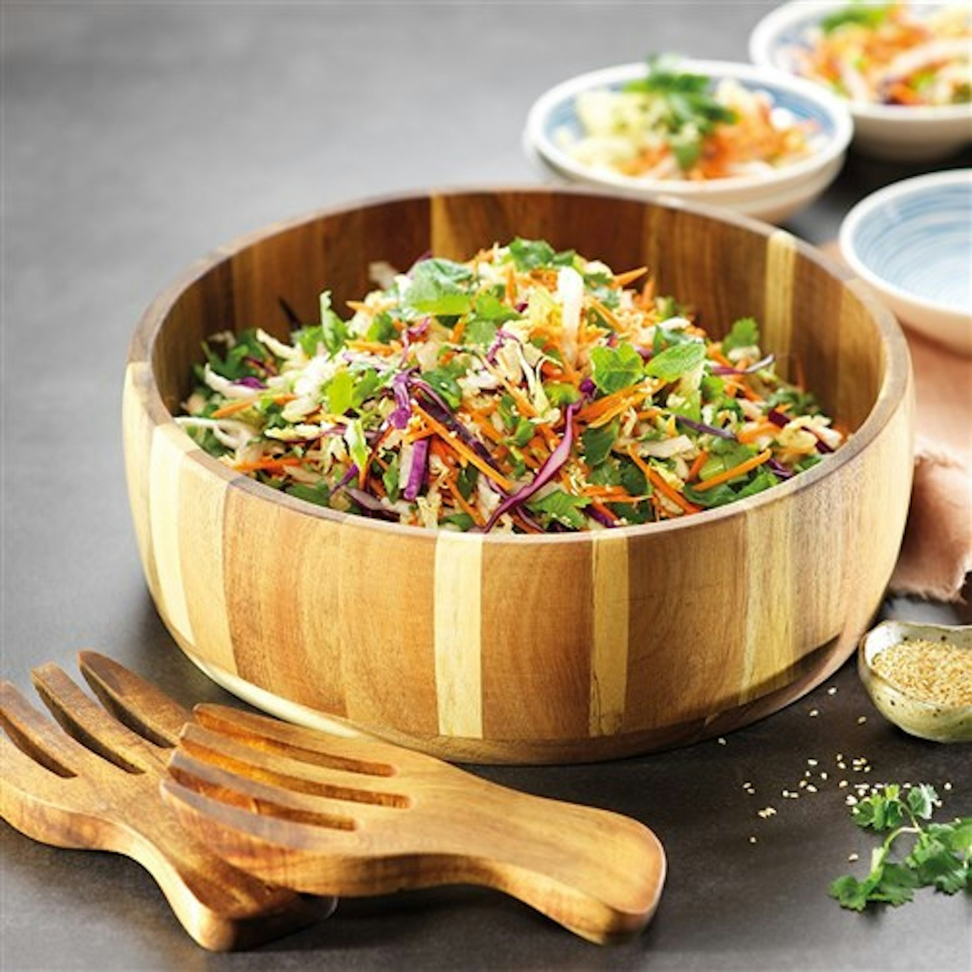 wooden salad bowl with wooden utensils filled with bright slaw salad