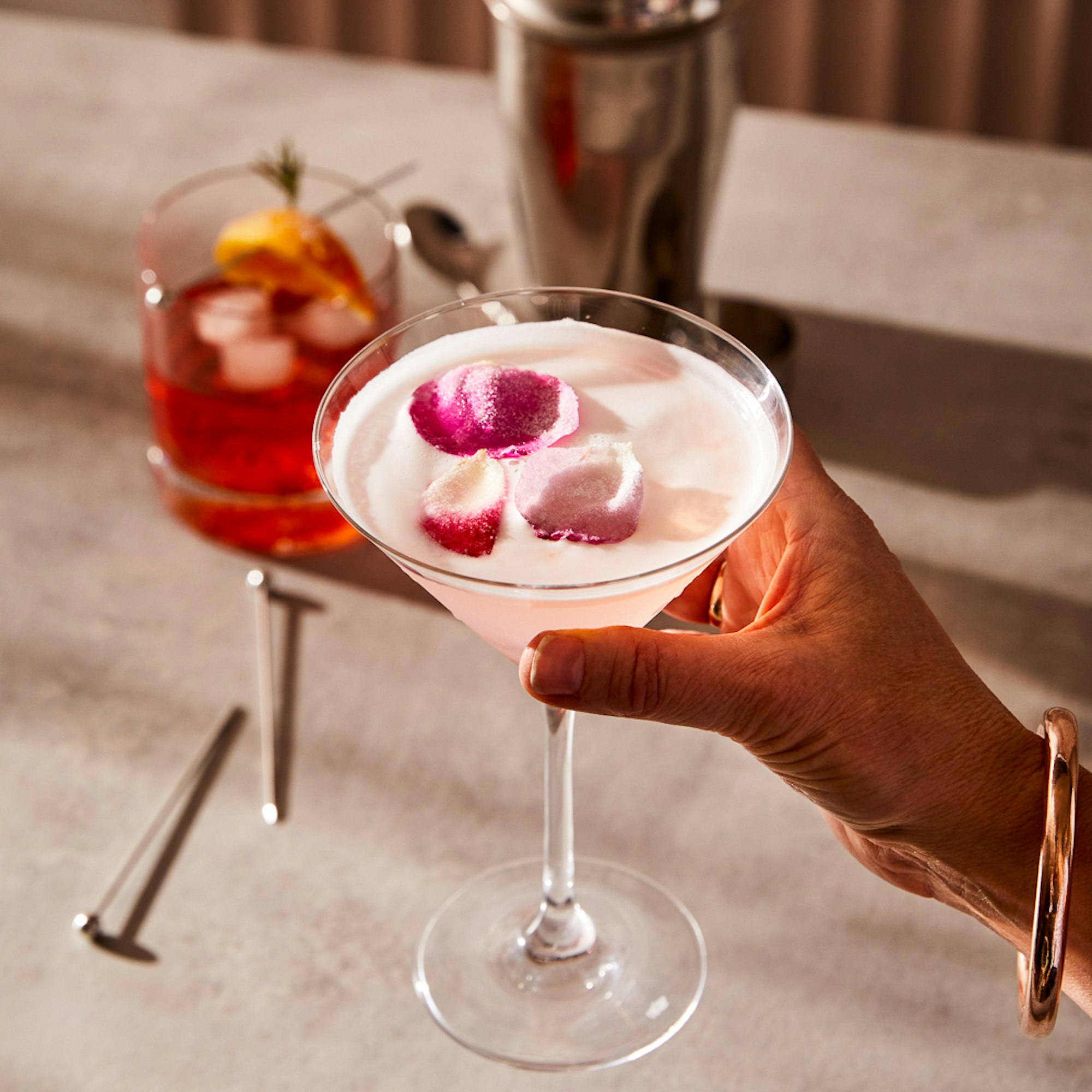 woman holding pink cocktail