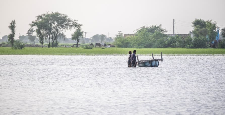 Two people walking through a large flooded plain