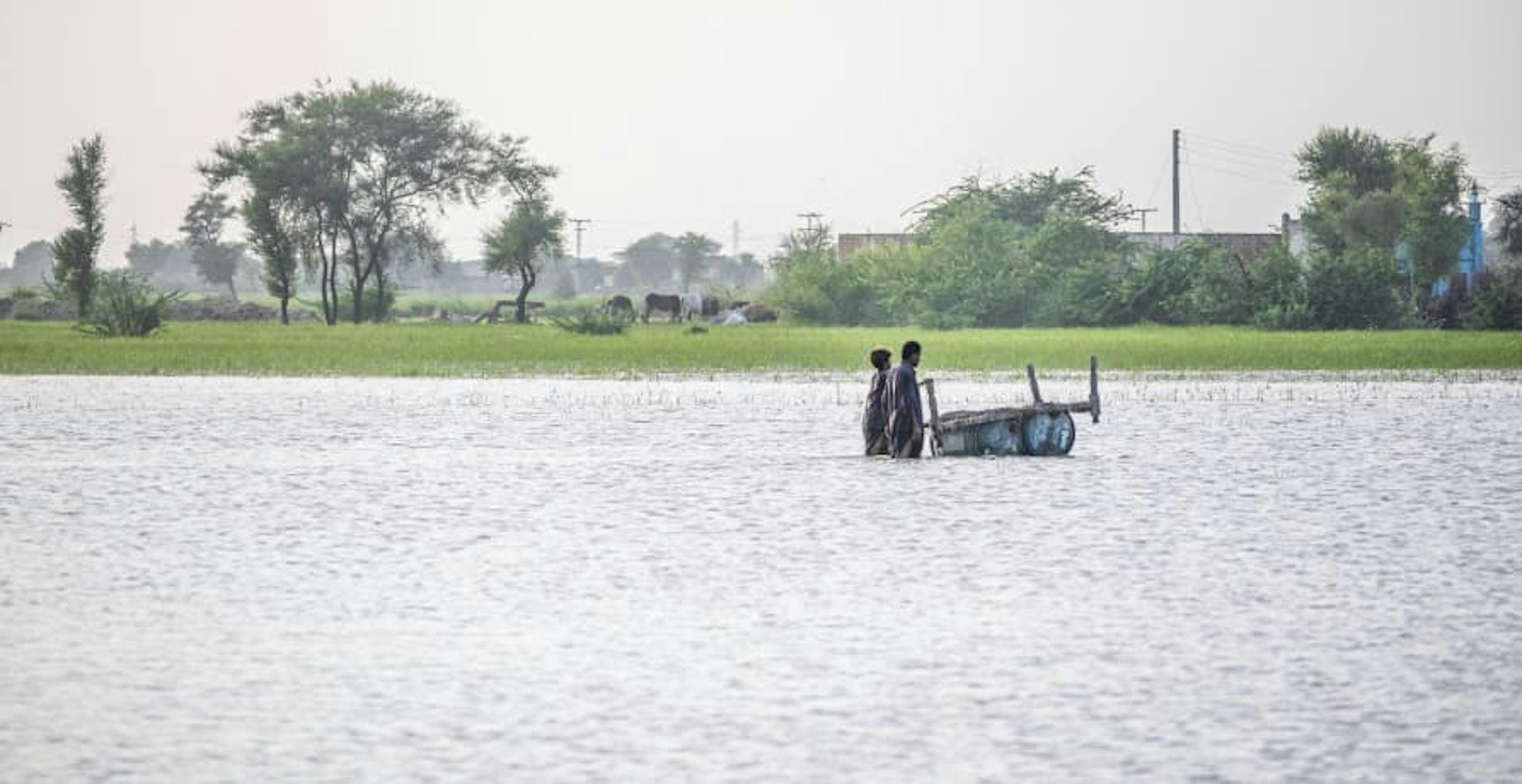 Two people walking through a large flooded plain
