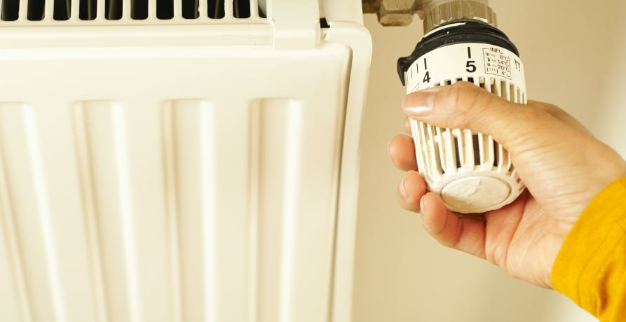 Une main en train de régler la température du radiateur