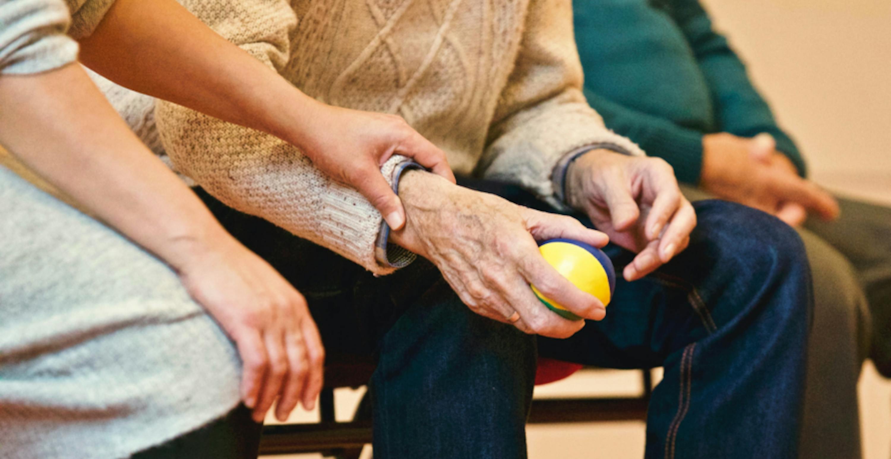 an elderly person sitting, someone holding their hand