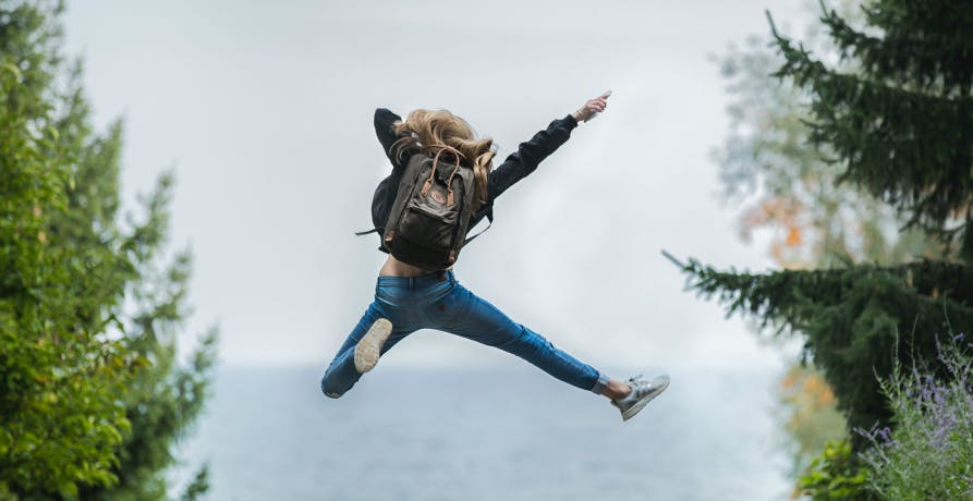 femme qui saute en l'air dans un paysage forestier