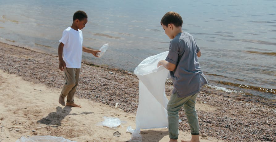 two boys collecting rubbish from beach