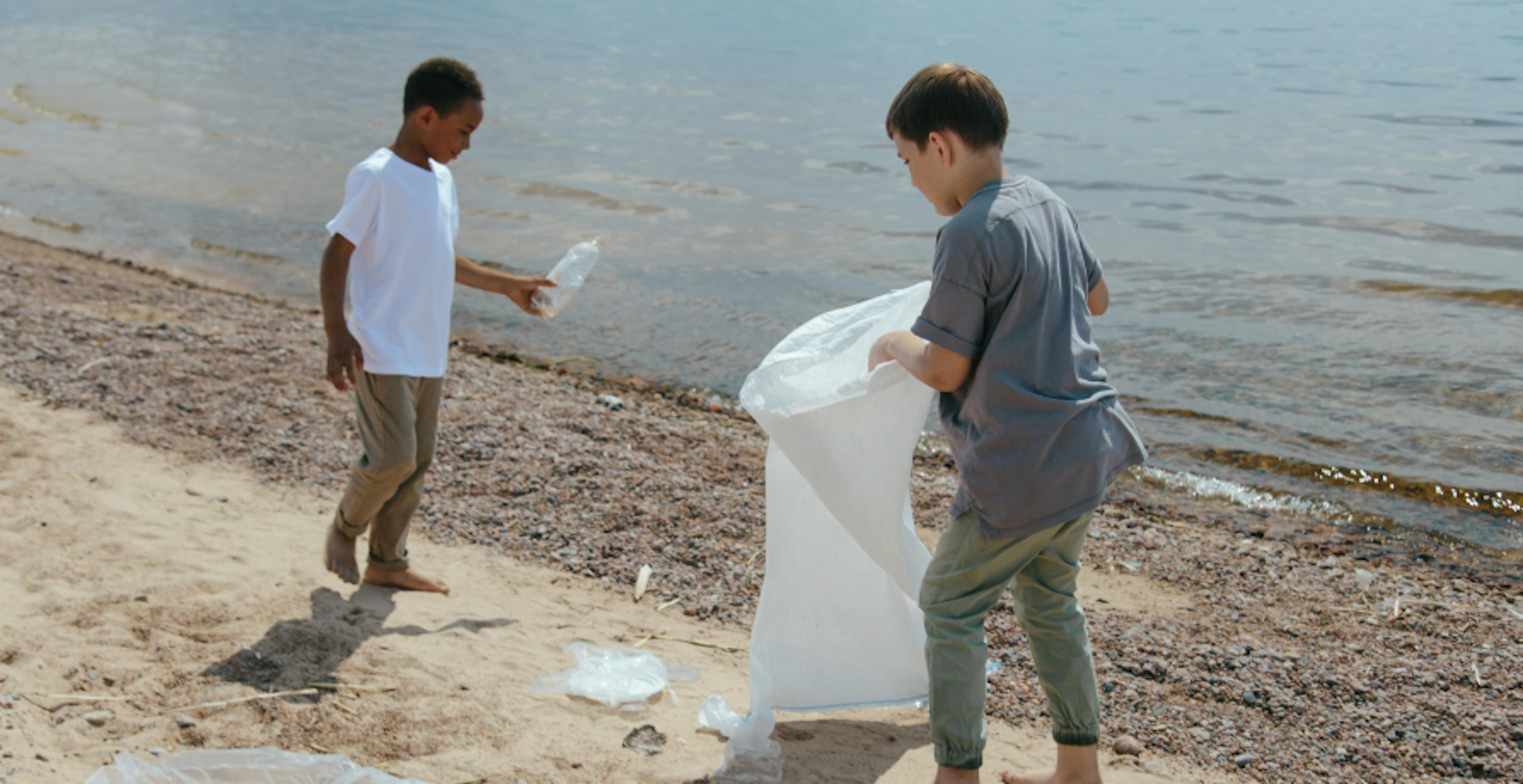 two boys collecting rubbish from beach