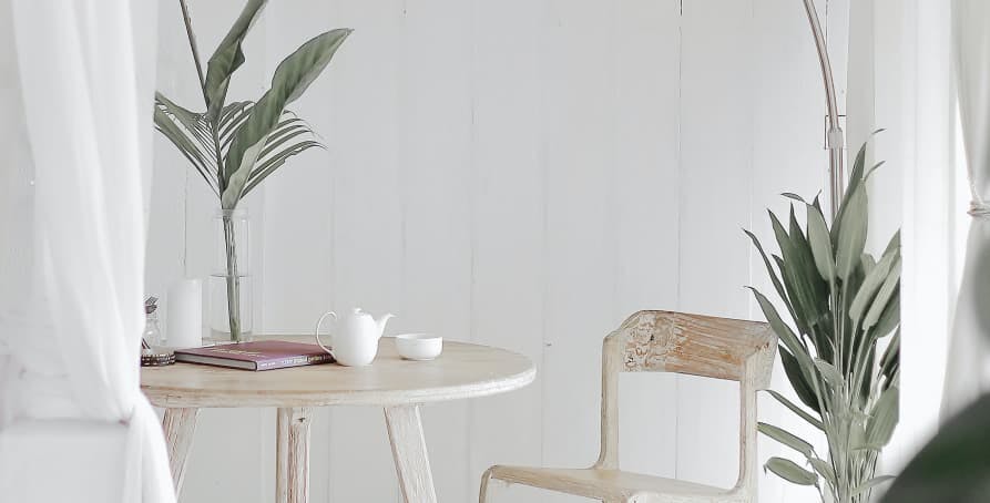 small wooden table with chair and muted, light green plants