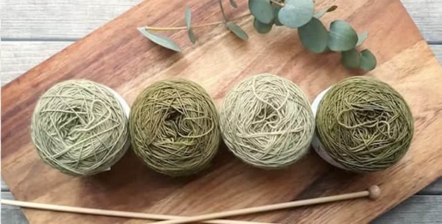 Four green yarns on chopping board