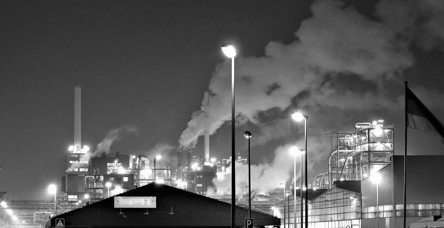 photo en noir et blanc de cheminées d'usines relâchant de la fumée dans l'air