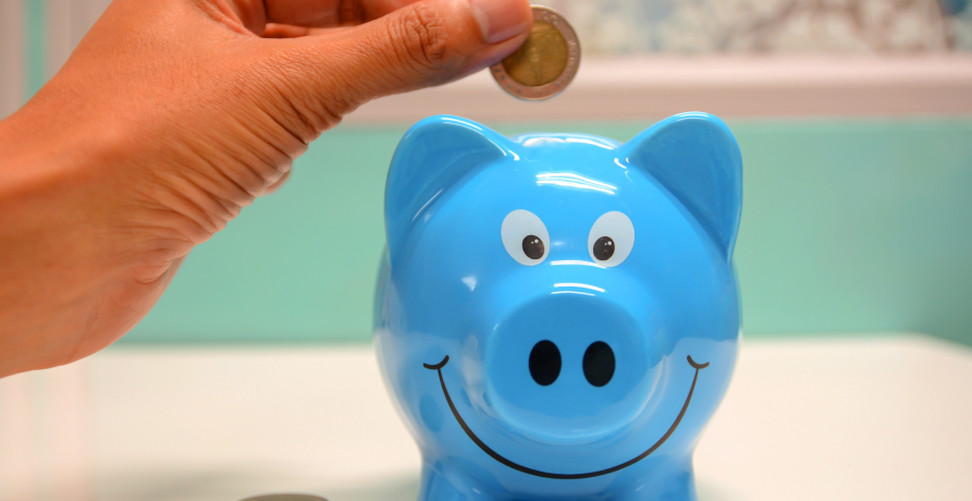 person putting coin in blue piggy bank