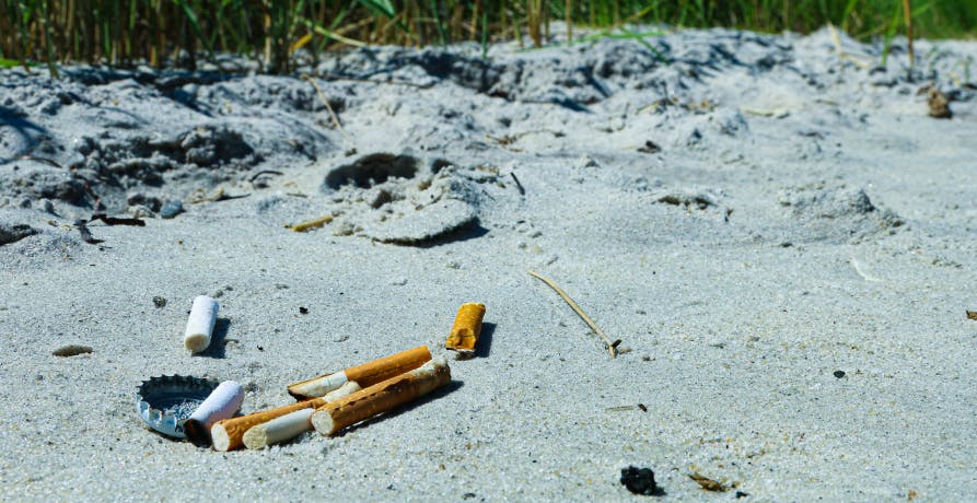 des mégots de cigarette dans le sable