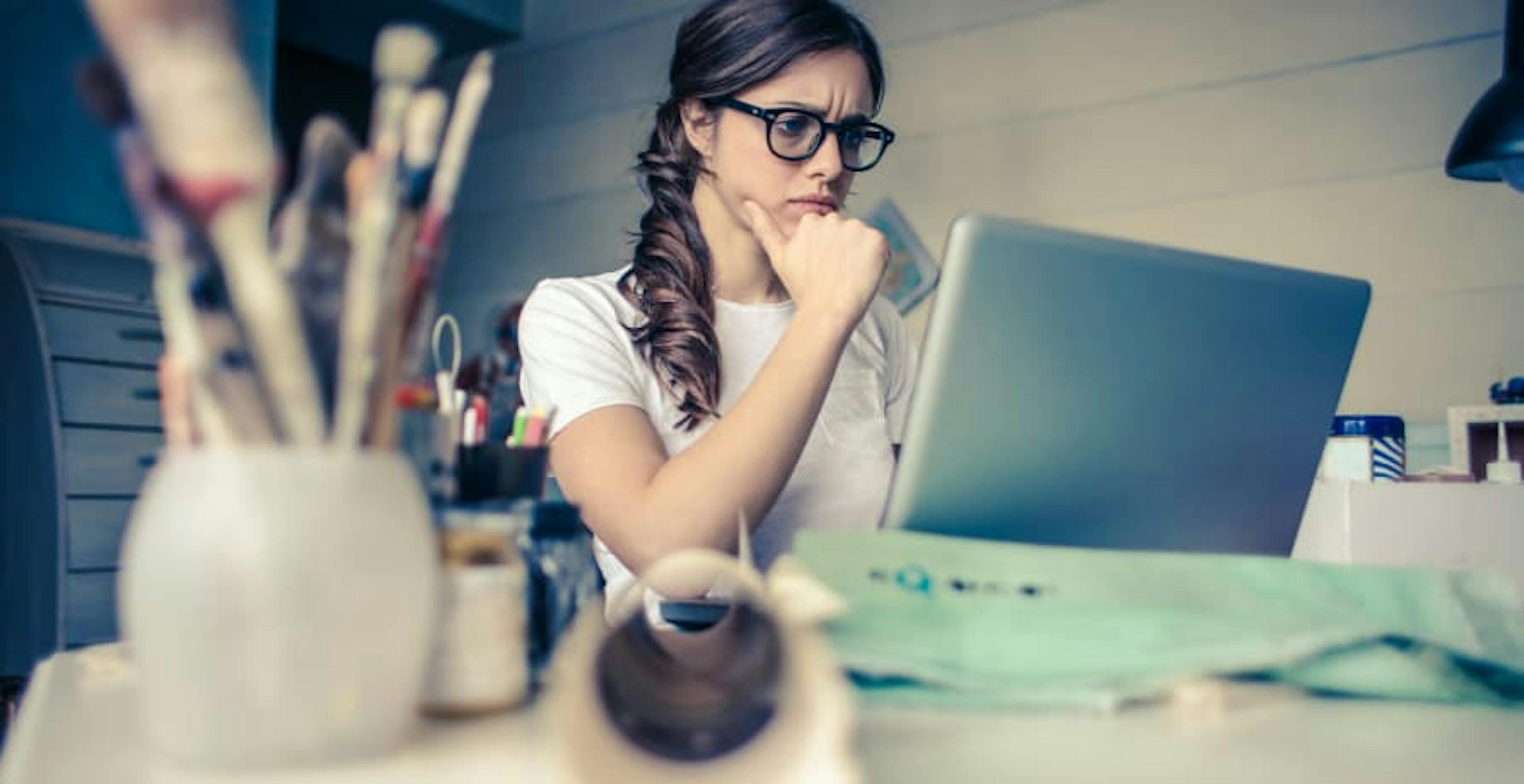 woman sitting at her desk, on her laptop, with an intense look on her face