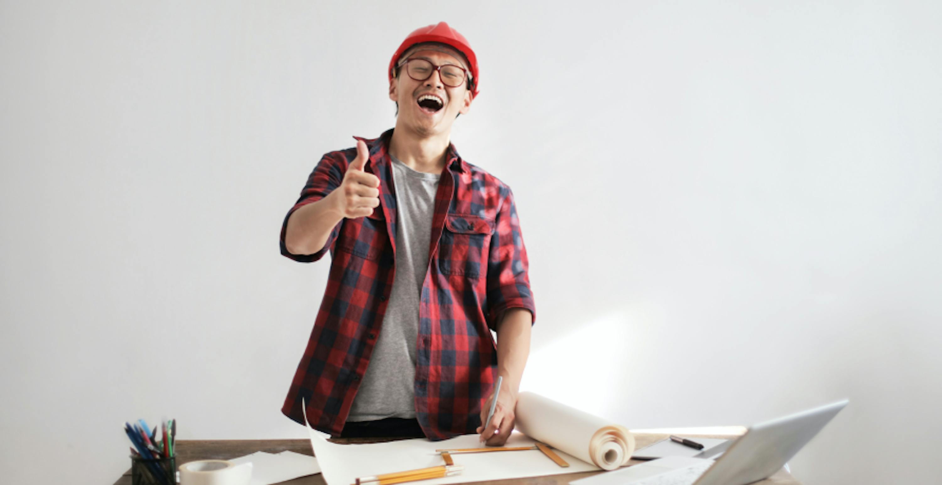 un ouvrier du bâtiment tout sourire et pouce en l'air travaillant sur un projet de construction