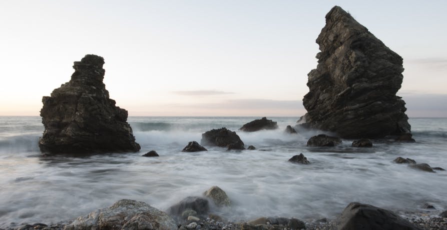 rocks with mist over body of water looking over the horizon