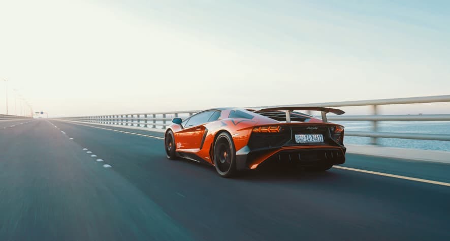 red racecar on bridge next to water