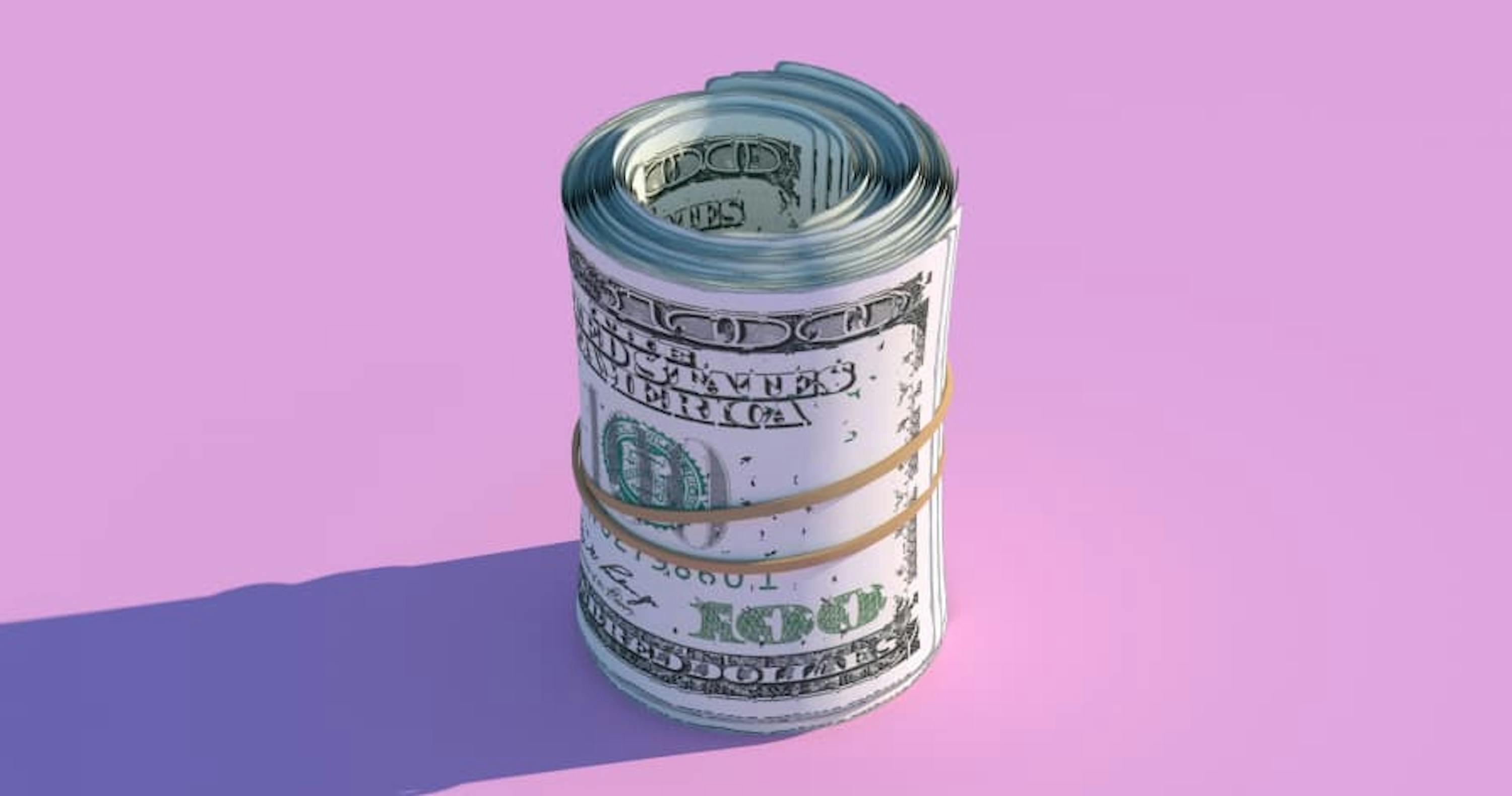 $100 USD bills rolled up in rubber band purple pink background