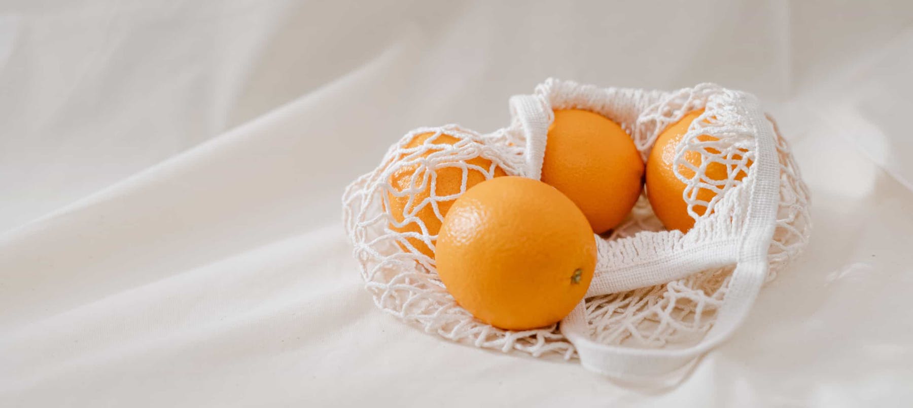 Four orange fruits in a Basket on white linen