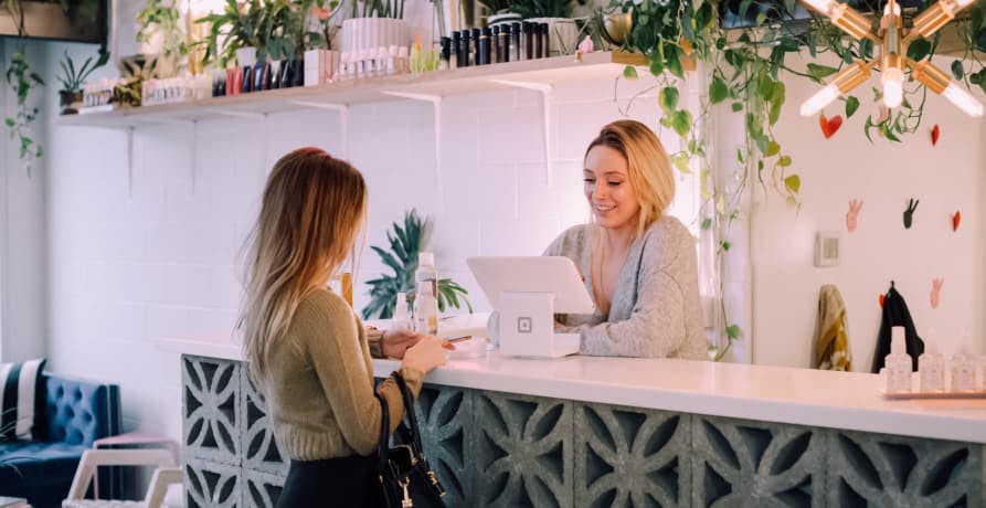 person at checkout counter with green plants hanging above