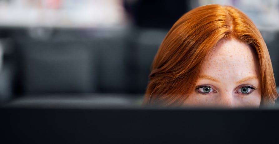 une femme rousse devant un écran d'ordinateur