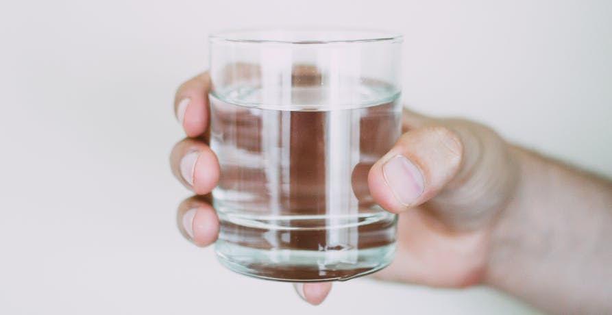 une personne tenant un verre d'eau dans la main