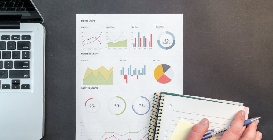 notepad, data on piece of paper, and laptop