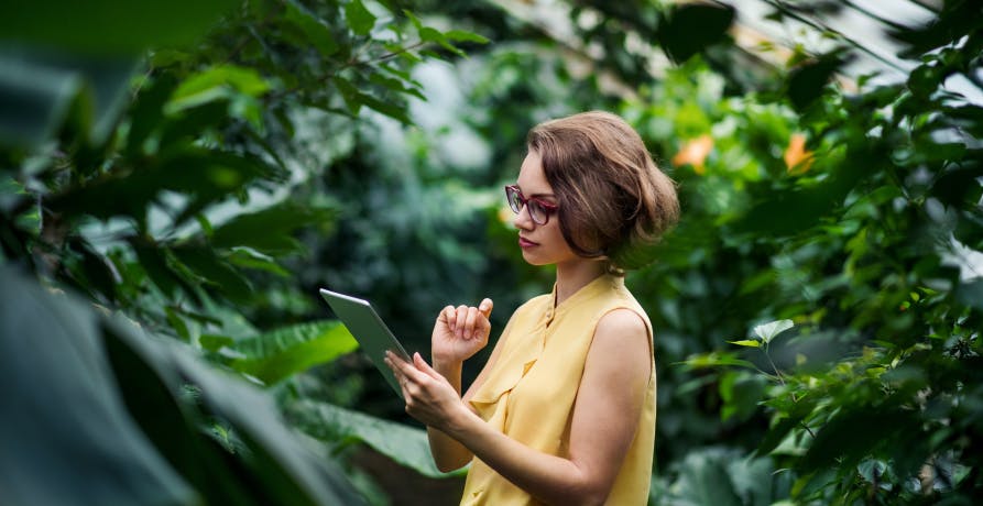 une femme utilisant une tablette numérique dans un décor végétal