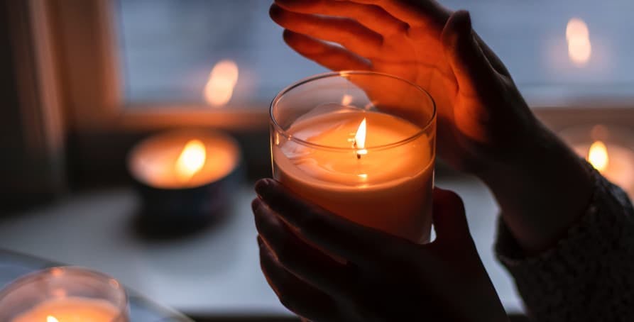 person holding a lit candle in jar