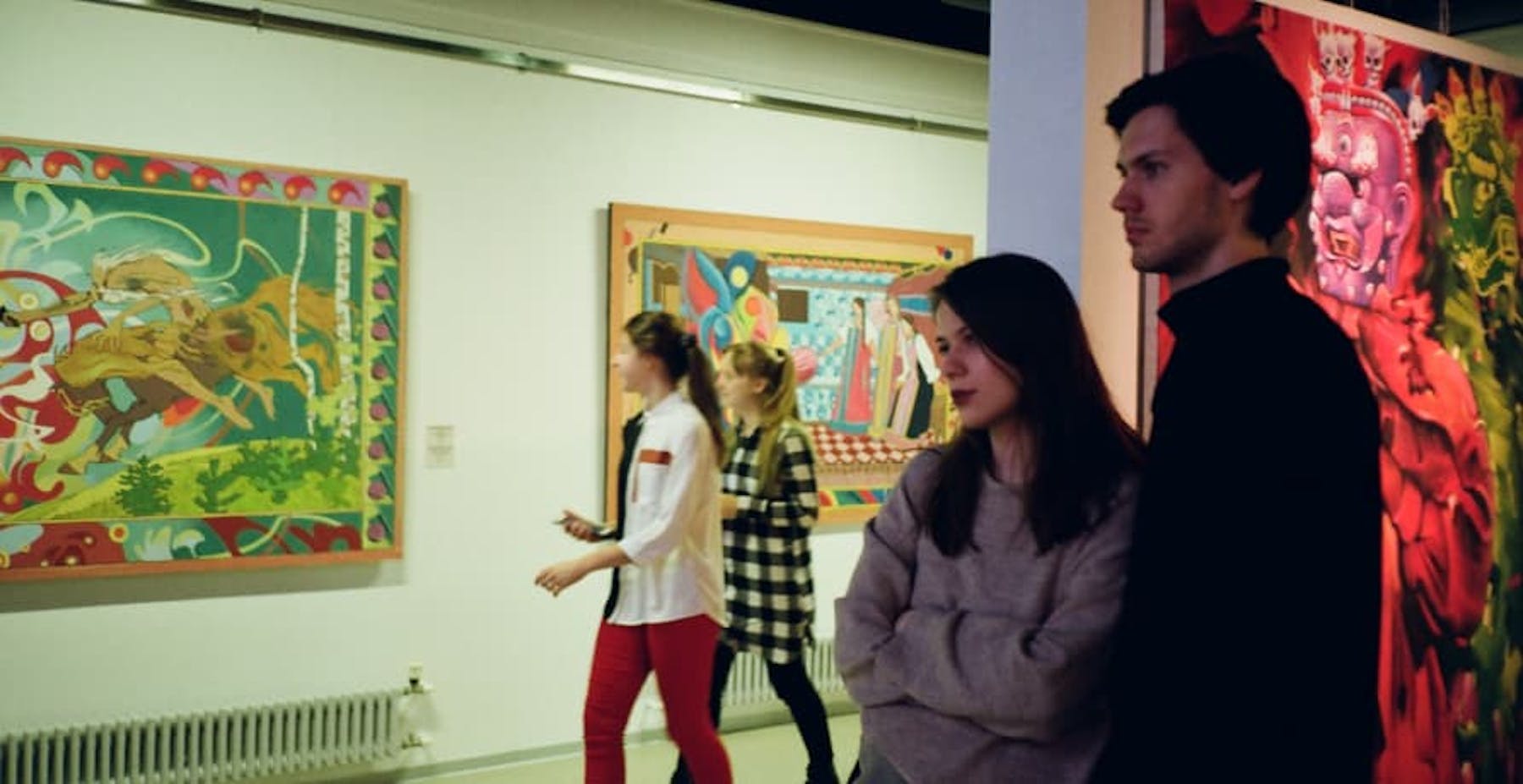 people looking at paintings inside modern art gallery