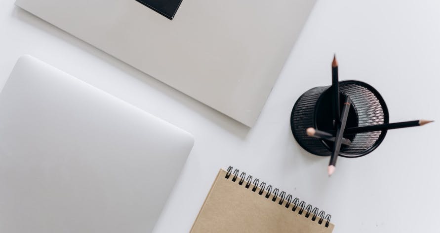 un bureau avec un ordinateur un calepin et un pot à crayon