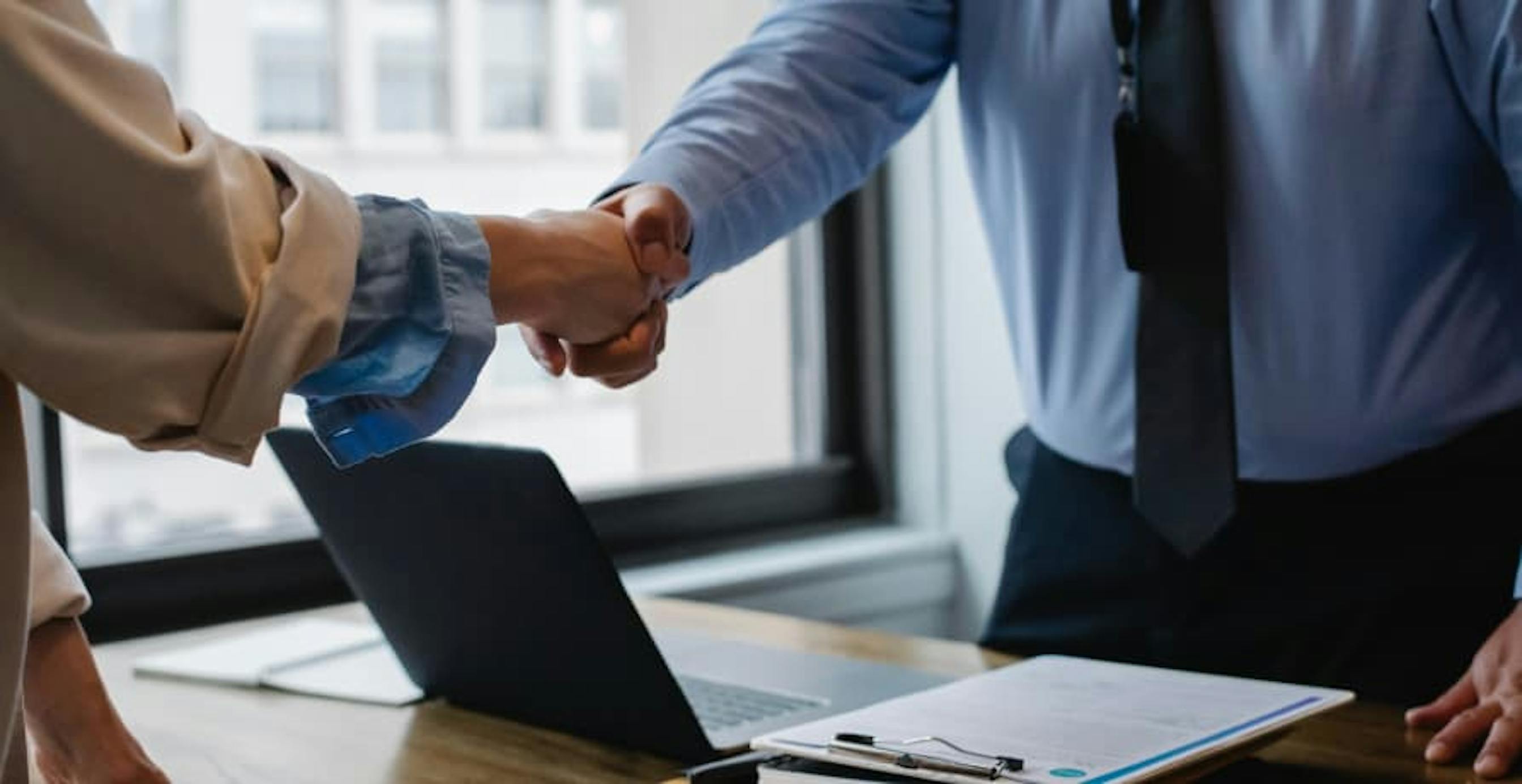 two business people shaking hands inside an office