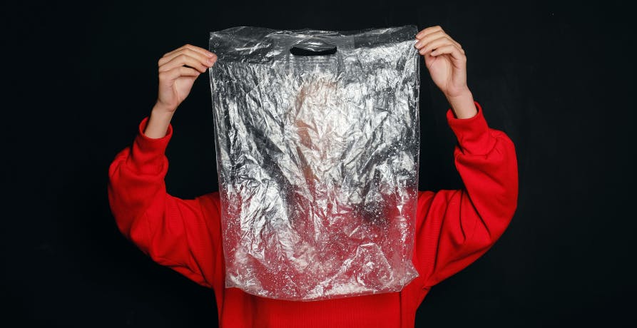 lady holding plastic bag to face wearing red sweater