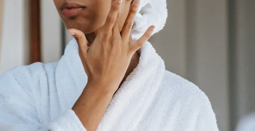 person in white robe applying skincare