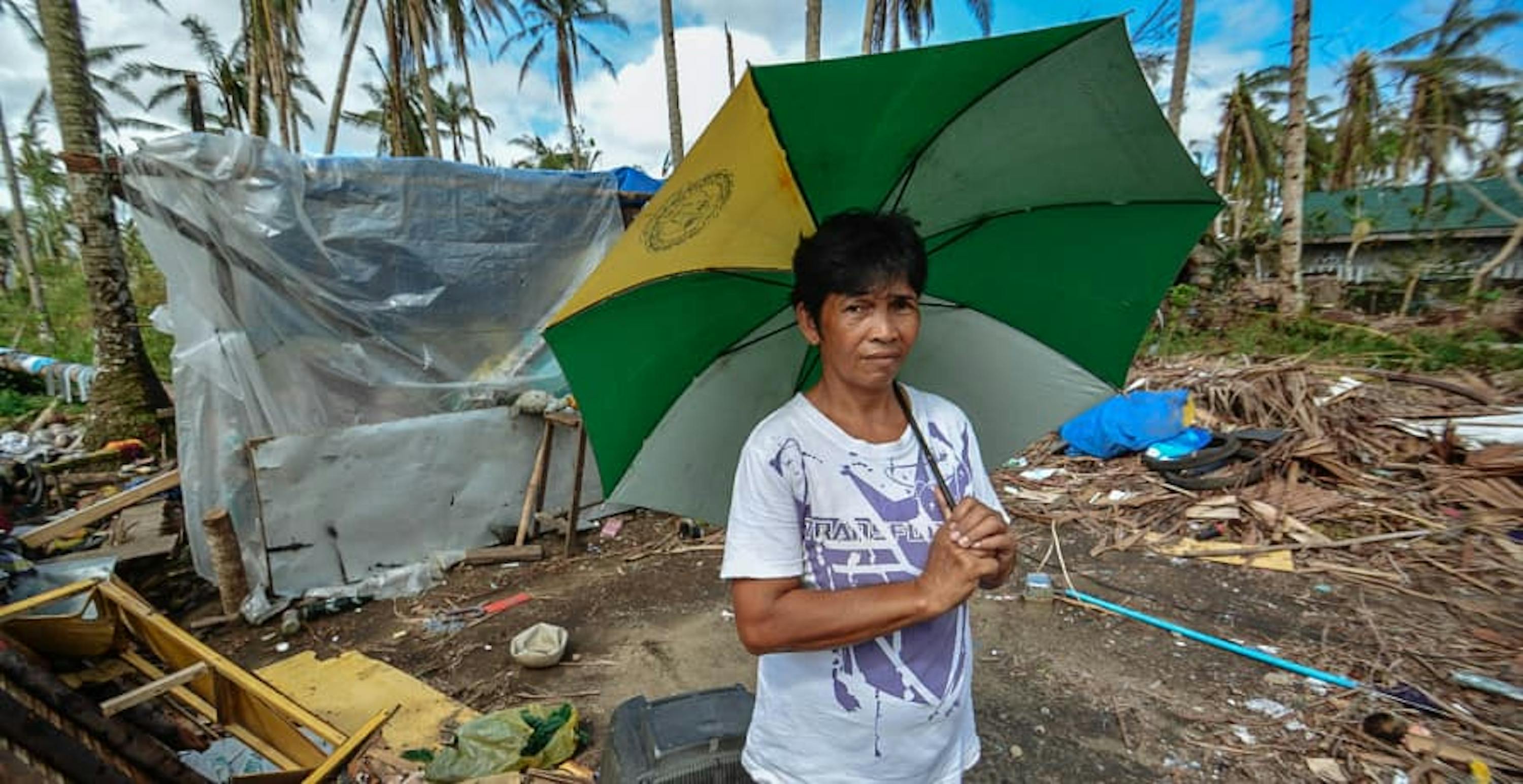 child holding up an umbrella and standing in a disaster zone 