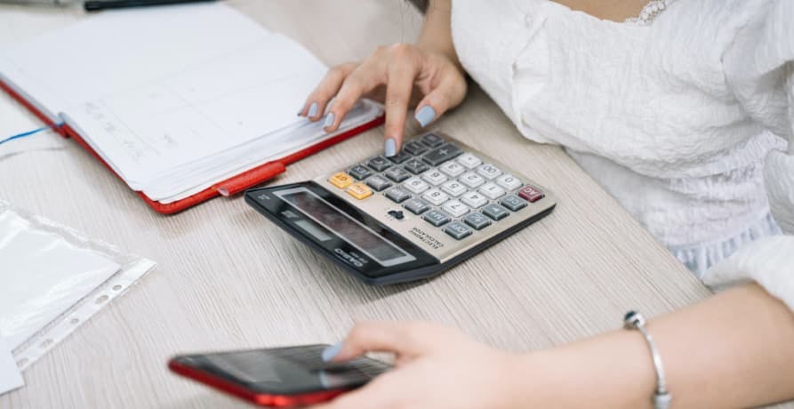 woman using her phone and calculator to do a calculation