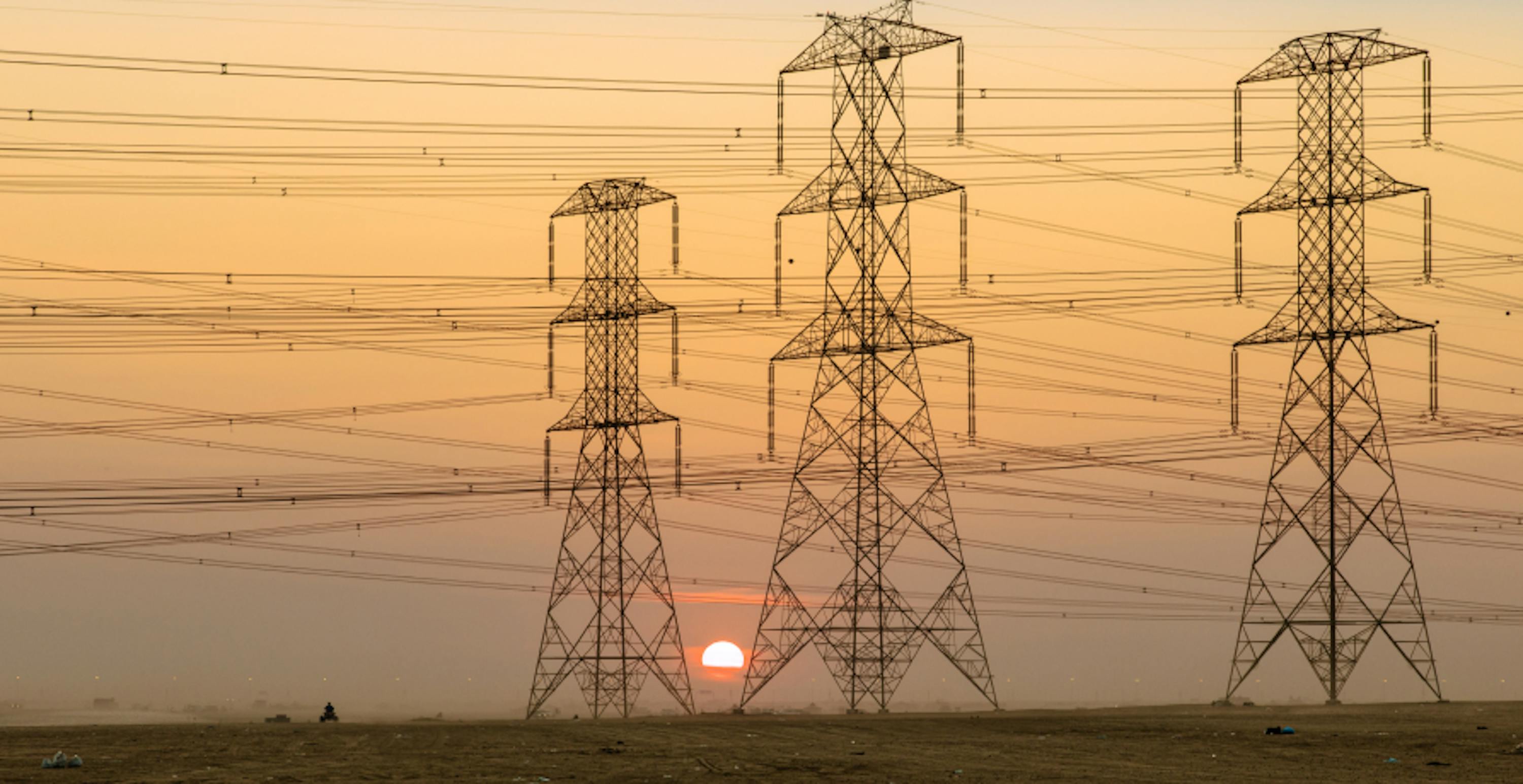 trois pylônes électriques devant un coucher de soleil