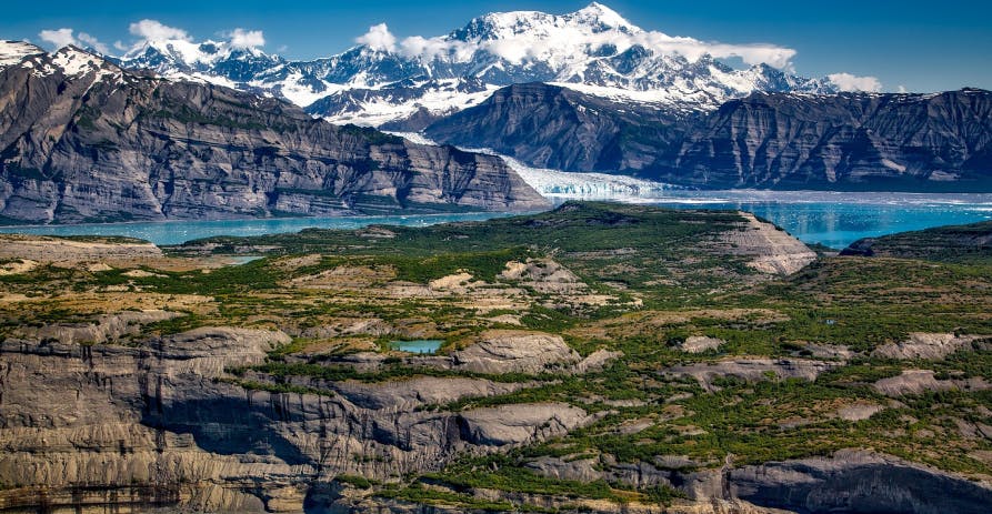 view of snowy mountains and rocks near blue water