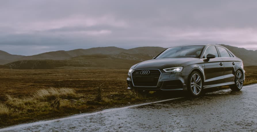 car parked at the side of a country road with hills