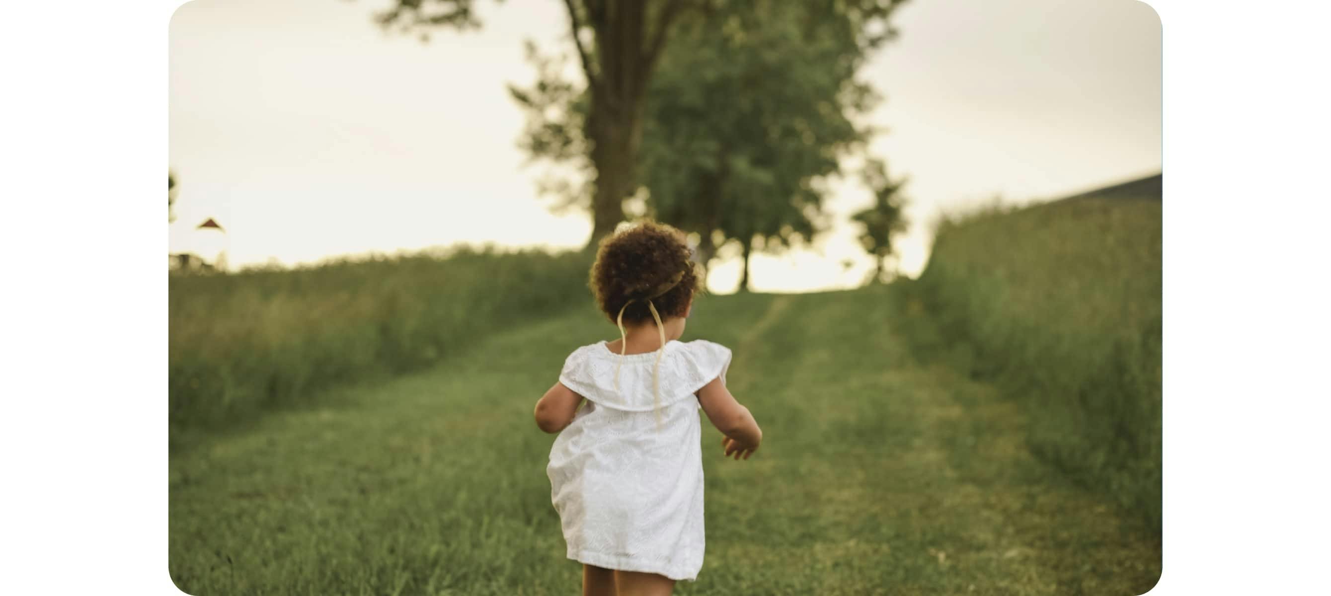 Girl standing on grass field facing trees