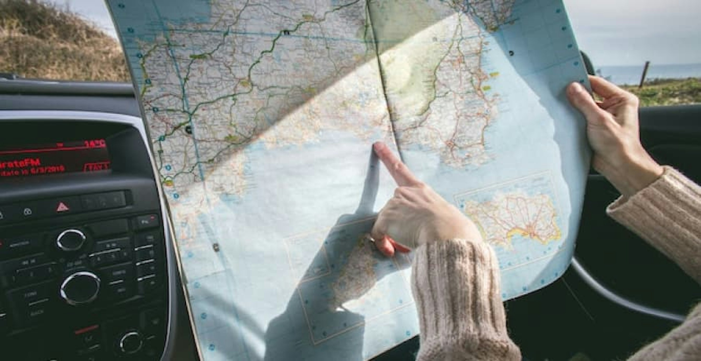 person with map in car pointing to destination